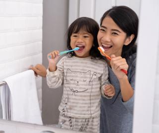 Child and mother brushing teeth together